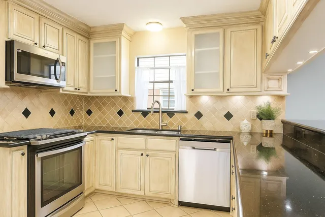 a kitchen with granite countertop white cabinets stainless steel appliances a sink and a window