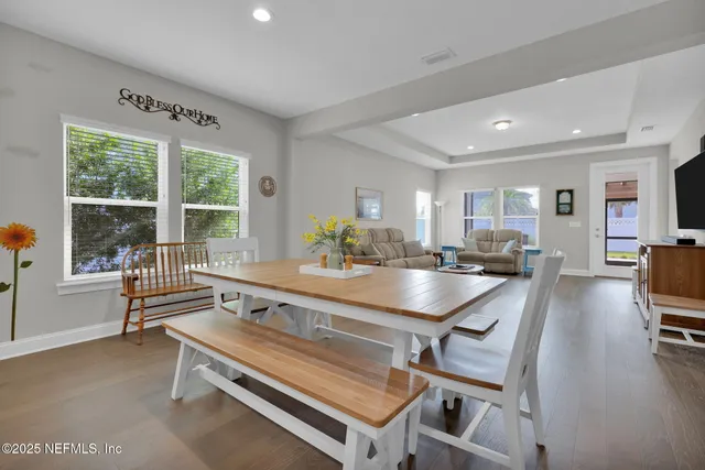 a dining hall with stainless steel appliances granite countertop a stove a sink a dining table and chairs with wooden floor