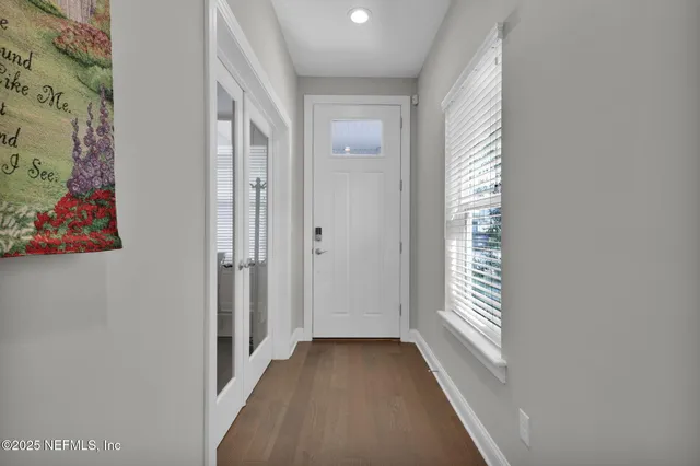 a view of a hallway with wooden floor and a bathroom