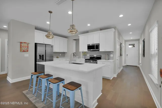 a kitchen with stainless steel appliances kitchen island granite countertop a refrigerator a stove a sink a microwave oven with a dining table and chairs