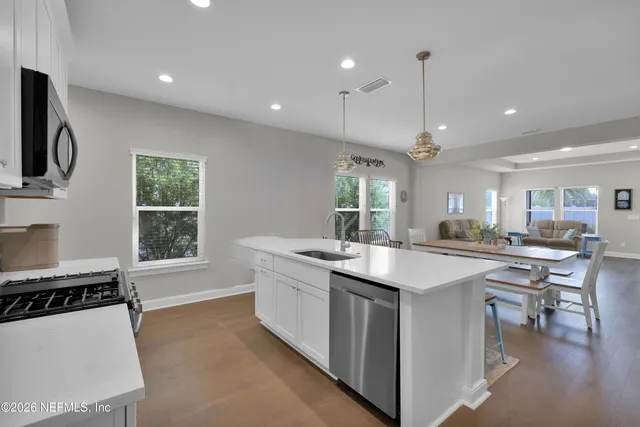 a kitchen with a stove a sink a window and chairs