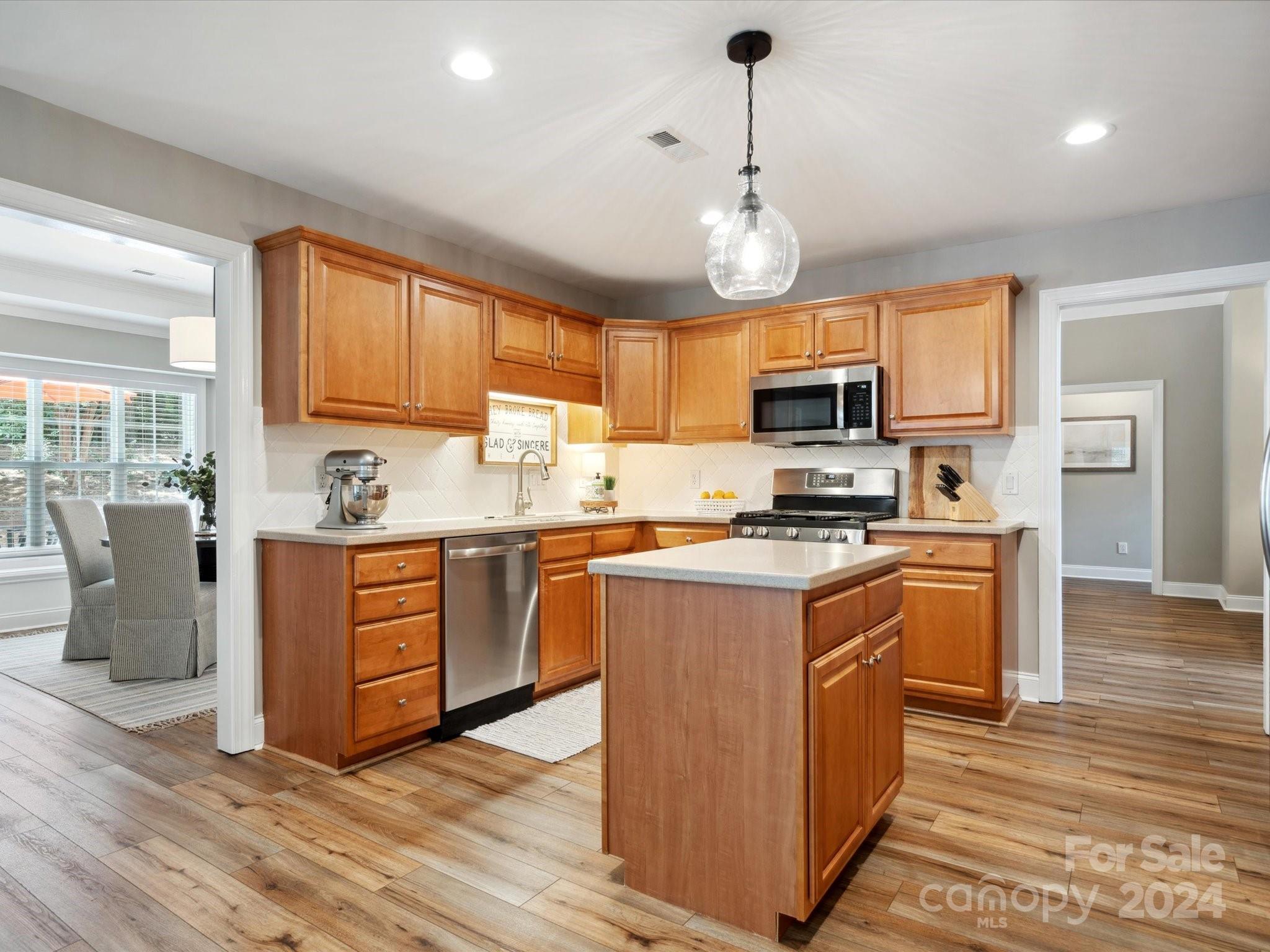 166 Zimmerman Drive Fort Mill, SC 29708 - Photo 11 of 30 a kitchen with stainless steel appliances granite countertop a stove top oven a sink dishwasher a refrigerator and a dining table with wooden floor