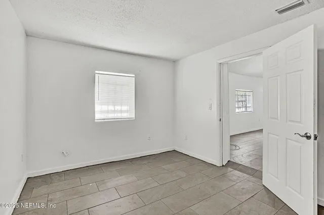 a view of an empty room with closet and a window
