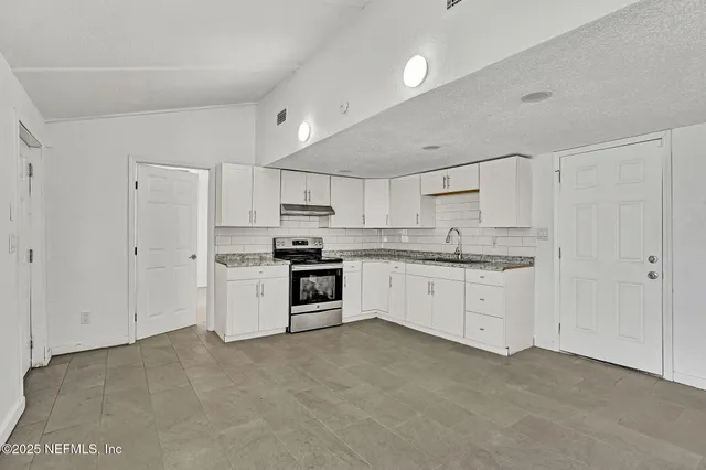 a kitchen with granite countertop white cabinets and stainless steel appliances
