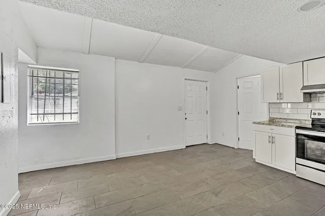a view of an empty room with a kitchen