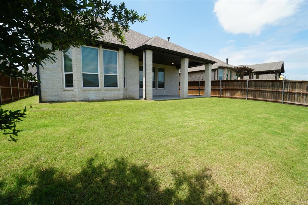 1309 Old Rocksprings Pass Mansfield, TX 76063 - Photo 31 of 36 Expansive backyard featuring a large green lawn, full privacy fencing, and a covered concrete patio