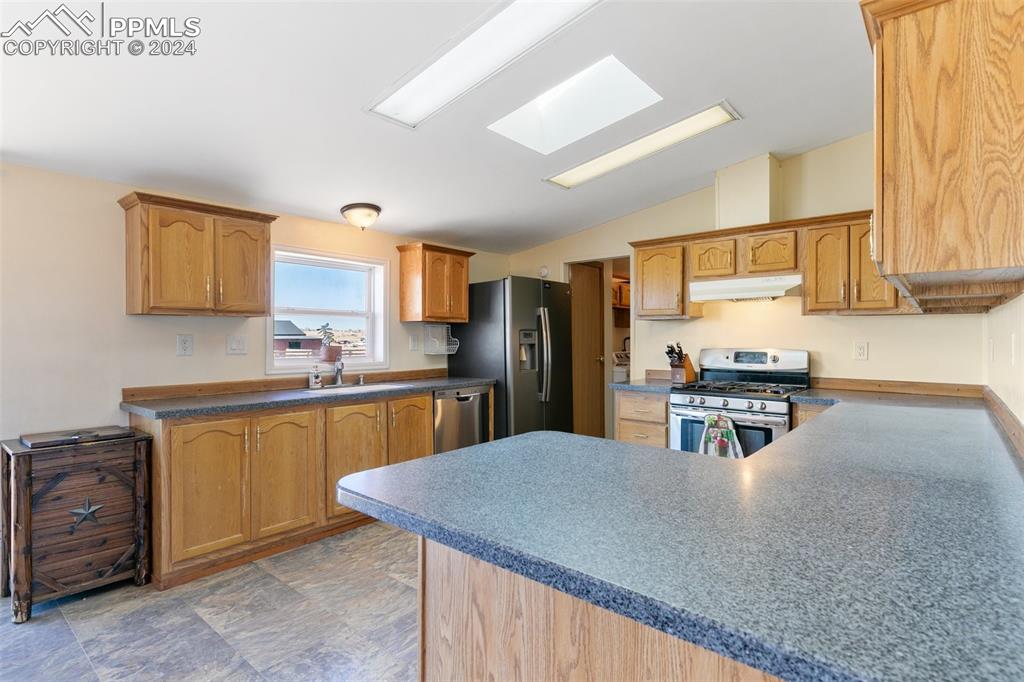 18830 Kevin's View Peyton, CO 80831 - Photo 17 of 37 Lofted ceiling with a skylight and window over the sink add to the open feel of this roomy kitchen.