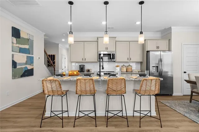 a view of kitchen with stainless steel appliances kitchen island granite countertop a dining table chairs and white cabinets
