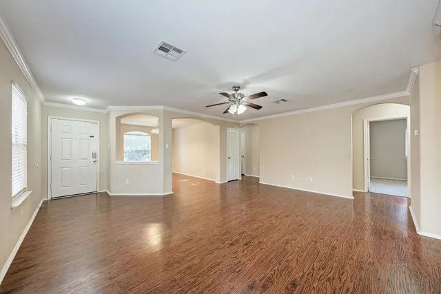an empty room with wooden floor chandelier and windows