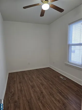 a view of an empty room with wooden floor and window