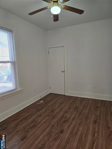 an empty room with wooden floor fan and windows