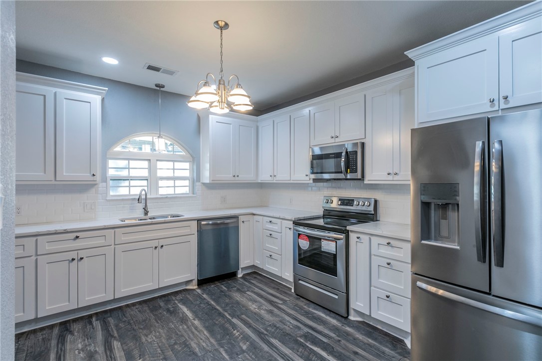 1007 North 22nd Street Waco, TX 76707 - Photo 6 of 26 a kitchen with stainless steel appliances granite countertop a stove a sink dishwasher a refrigerator and white cabinets with wooden floor