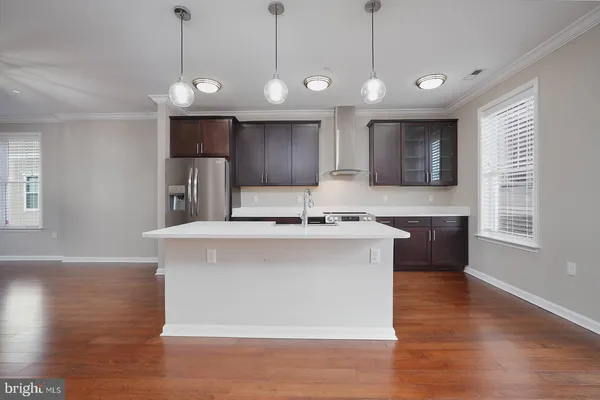 a view of kitchen with stainless steel appliances granite countertop a sink a microwave oven a refrigerator and wooden floor