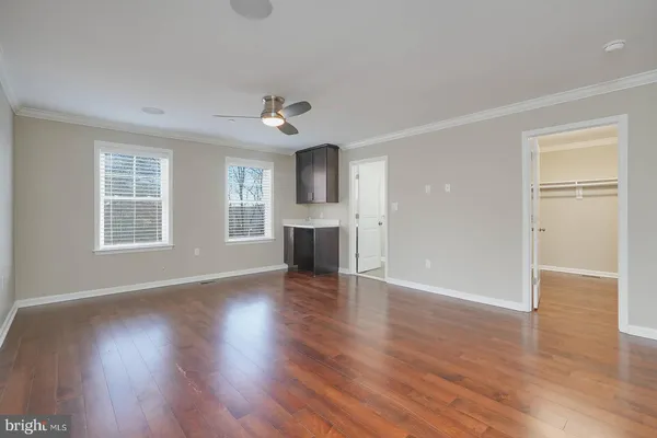 an empty room with wooden floor chandelier and windows
