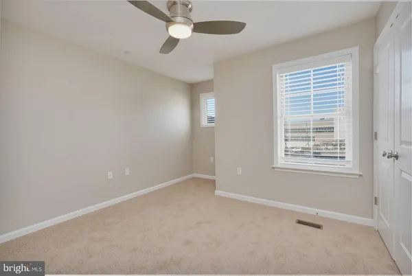 an empty room with a window and ceiling fan