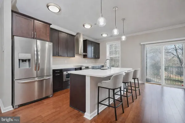 a kitchen with stainless steel appliances granite countertop a refrigerator a sink a stove and a refrigerator