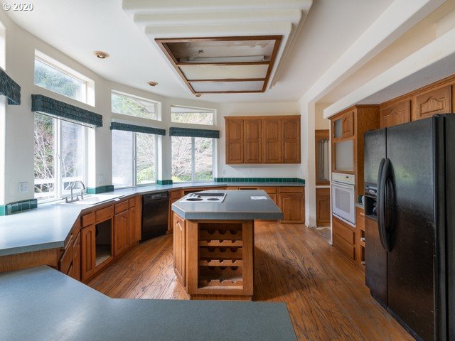 65477 Elk Ridge Road North Bend, OR 97459 - Photo 8 of 32 a kitchen with stainless steel appliances granite countertop a refrigerator a sink dishwasher a stove and white countertops with wooden floor