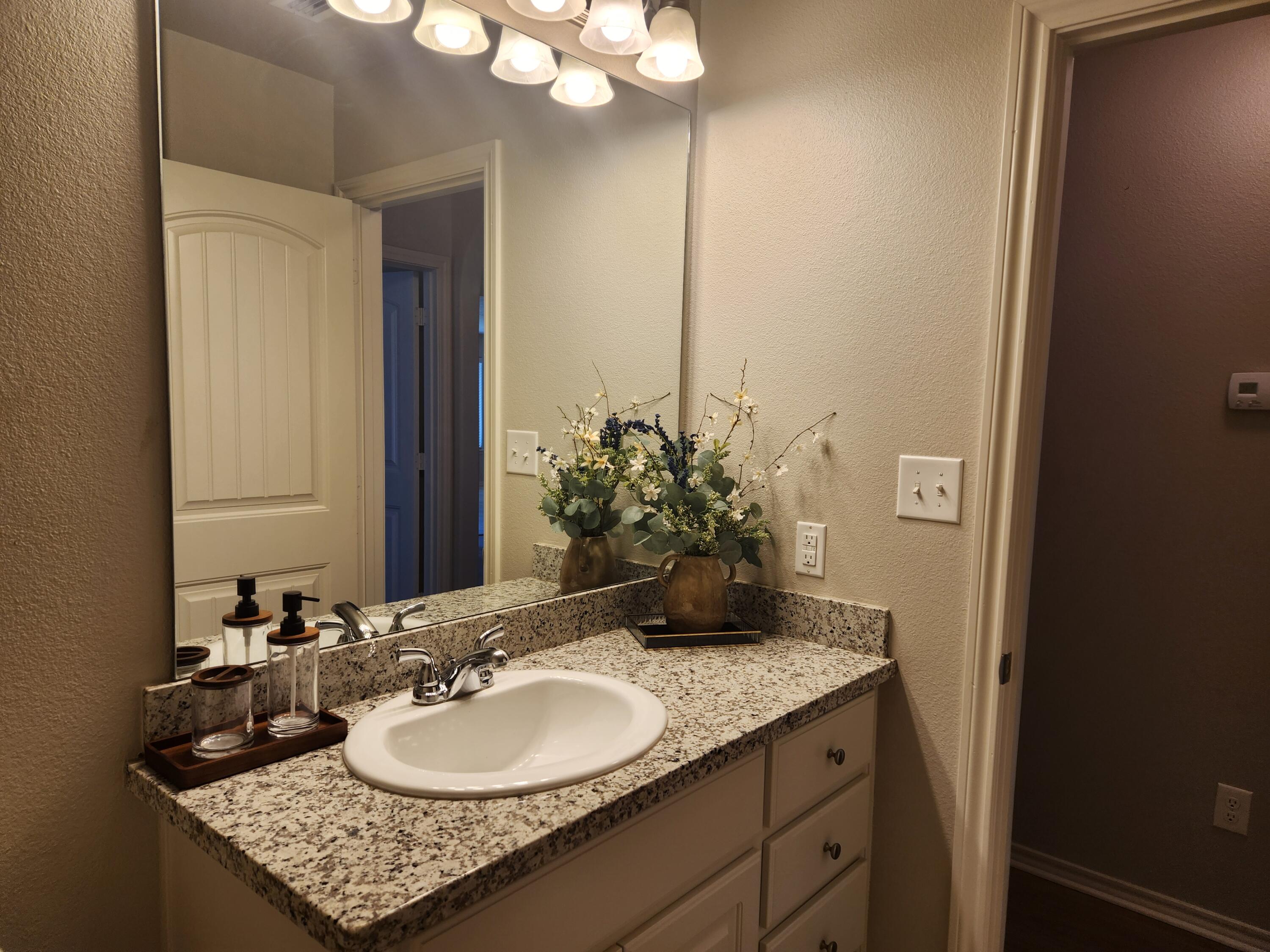 8702 13th Street Lubbock, TX 79416 - Photo 16 of 25 a bathroom with a granite countertop sink and a mirror