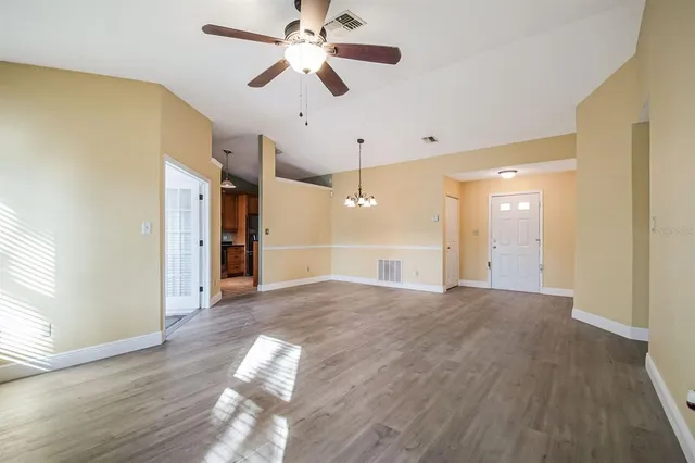 a view of empty room with wooden floor and fan