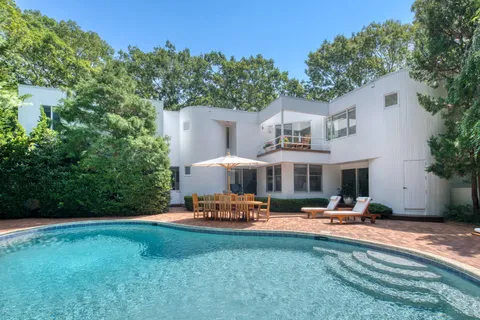 a view of a patio with table and chairs potted plants and large tree