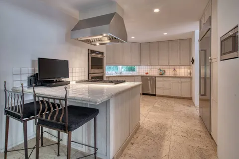 a kitchen with kitchen island granite countertop a sink counter top space appliances and cabinets
