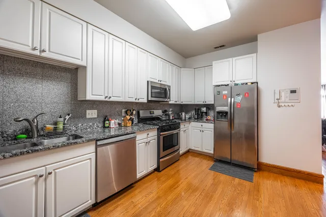 a kitchen with stainless steel appliances granite countertop a refrigerator a stove top oven a sink and cabinets