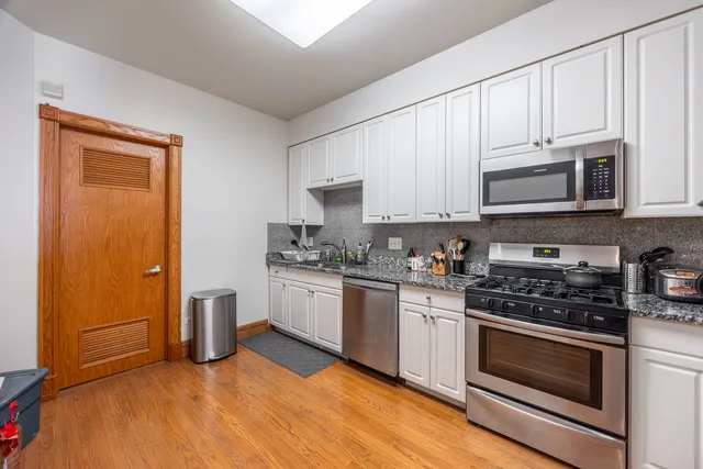 a kitchen with granite countertop white cabinets and stainless steel appliances
