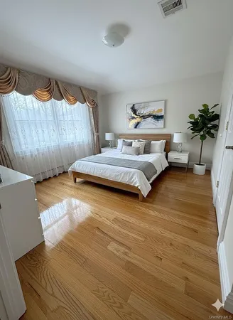 a bedroom with a bed and a potted plant on the dresser