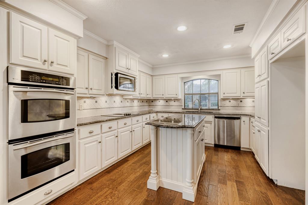 6108 Bluff Point Drive Dallas, TX 75248 - Photo 7 of 28 a kitchen with kitchen island granite countertop appliances cabinets and a wooden floor