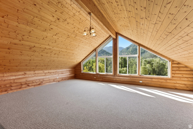 2640 East Weber Canyon Road Oakley, UT 84055 - Photo 29 of 56 Vaulted wood-paneled ceilings, log wall accents, expansive triangular windows, recessed lighting, and neutral carpeting