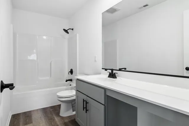 a bathroom with a granite countertop sink a toilet and a large mirror