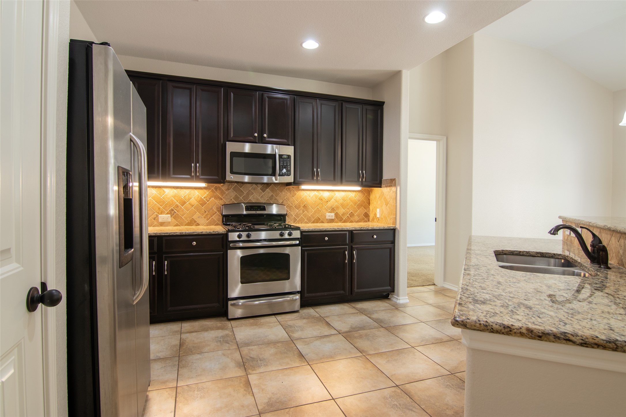 12104 Broten Street Austin, TX 78748 - Photo 9 of 32 An inviting kitchen features rich cabinetry, stainless appliances, and polished stone countertops.