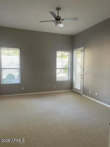an empty room with windows and fan