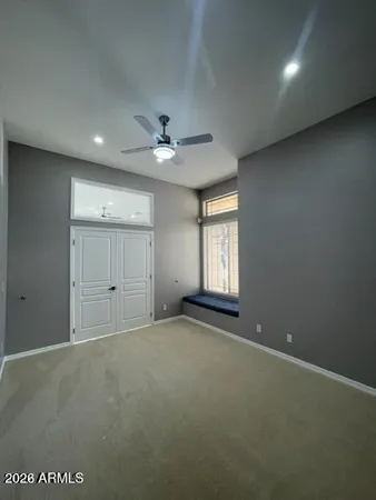 an empty room with windows and ceiling fan