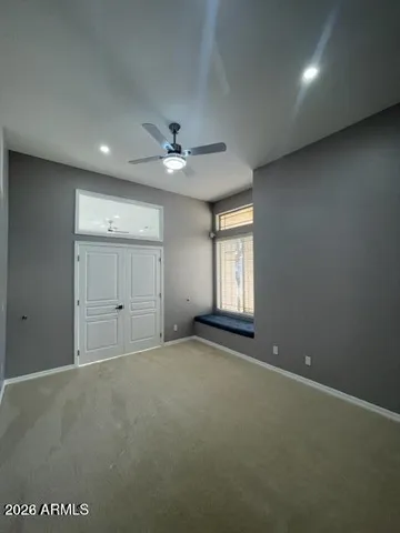 an empty room with windows and ceiling fan