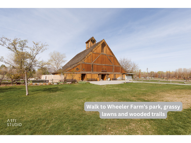 6761 950 East Midvale, UT 84047 - Photo 44 of 44 Expansive green space featuring a large wooden barn structure with a prominent gabled roof and cupola, surrounded by mature trees and a fenced perimeter