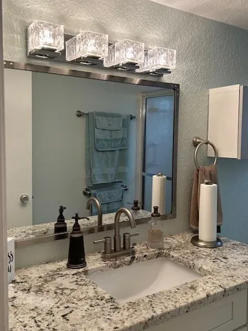 a bathroom with a granite countertop sink and a mirror