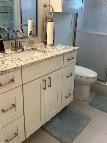 a bathroom with a granite countertop toilet and sink