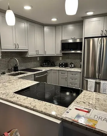 a kitchen with kitchen island granite countertop a sink a stove and cabinets