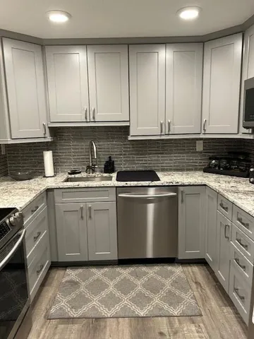 a kitchen with granite countertop white cabinets and stainless steel appliances