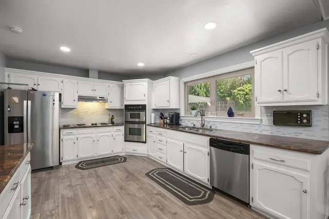 a kitchen with granite countertop white cabinets and white stainless steel appliances