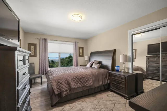 a bedroom with a bed wooden floor and flat screen tv