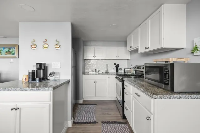 a kitchen with granite countertop a sink stainless steel appliances and white cabinets
