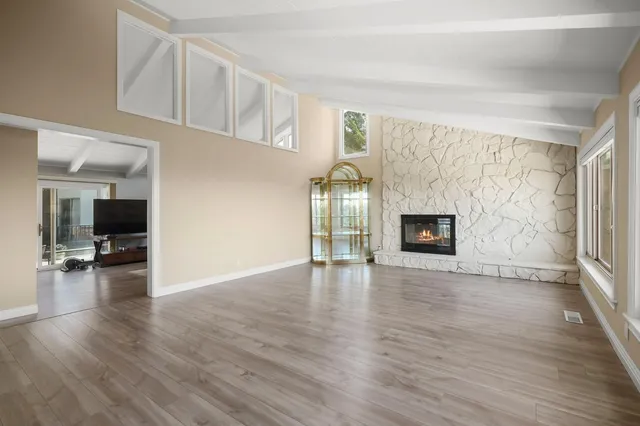 a view of empty room with wooden floor and fireplace