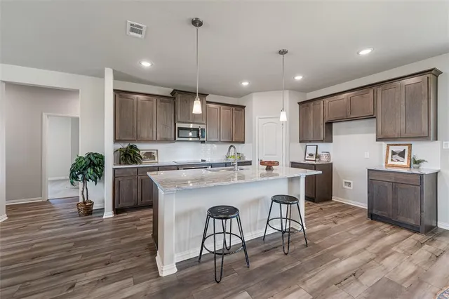 a kitchen with kitchen island granite countertop wooden floors and stainless steel appliances