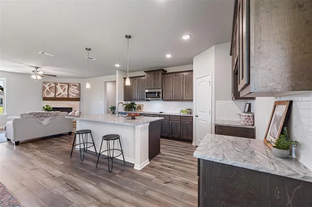 a kitchen with kitchen island granite countertop a sink a counter top space and stainless steel appliances