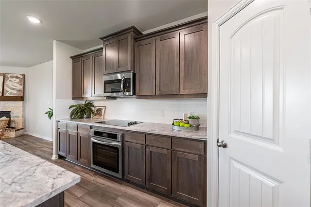 a kitchen with stainless steel appliances a stove a sink cabinets and a wooden floor