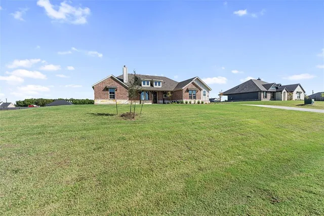 a front view of a house with a big yard and potted plants
