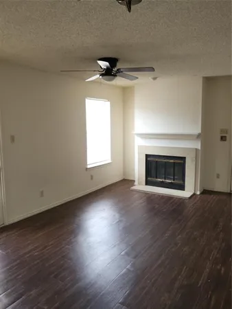 an empty room with wooden floor fireplace and windows
