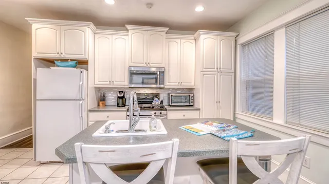 a kitchen with a refrigerator a stove a sink and chairs